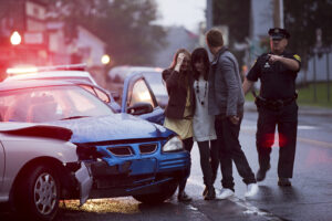 Young people and police officer at scene of car crash